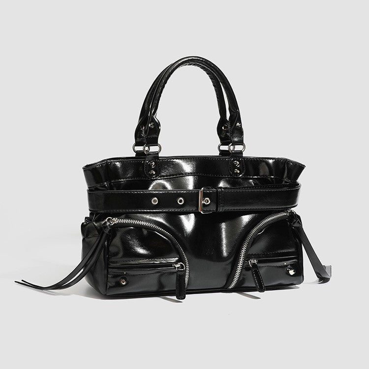 Black glossy structured tote bag with rivet and buckle detail, dual top handles, and detachable shoulder strap, detail view 4