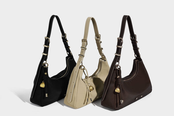 Crescent hobo shoulder bag in pebbled leather-look finish with top zipper, adjustable strap, gold-tone ring hardware, and