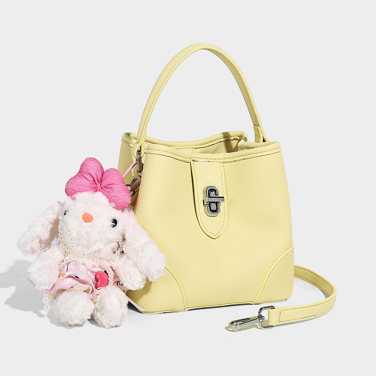 Small structured pebbled bucket bag with flap turn-lock closure, short top handle, and detachable shoulder strap, front view