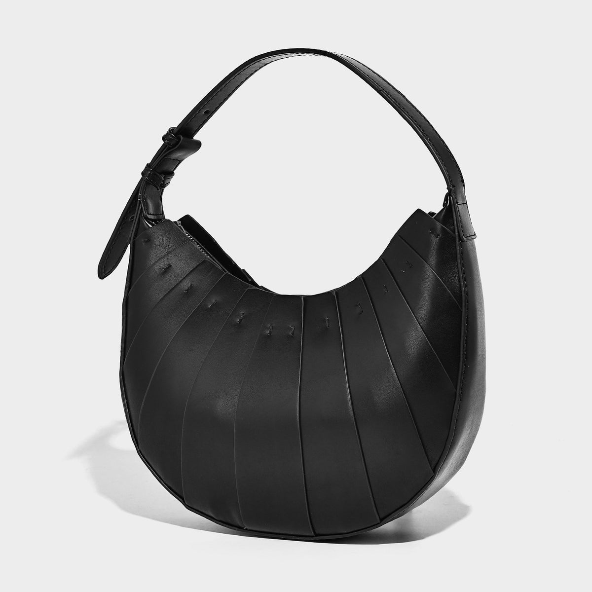 Crescent half-moon shoulder bag with vertical panel seaming, matte-satin leather-look finish, and adjustable gold-tone