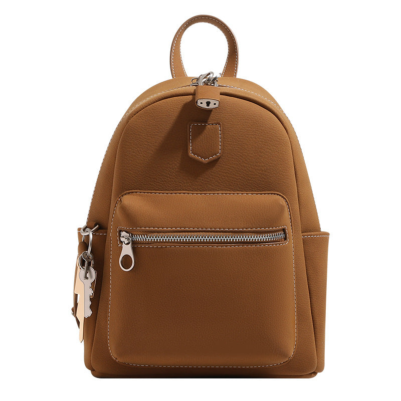 Small rounded mini backpack handbag in pebbled leather-look finish with front zip pocket, silver-tone hardware, and, detail