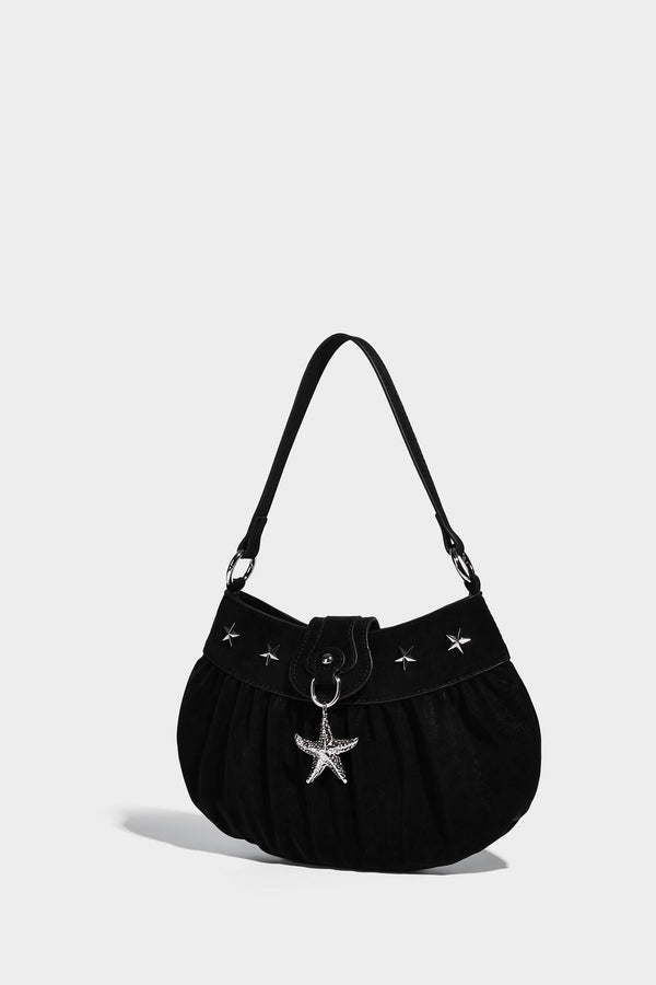 Ruched shoulder bag with curved flap, silver star studs, dangling starfish charm, and adjustable crossbody strap, detail view