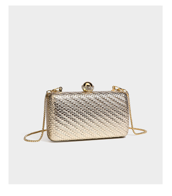 Small structured metallic woven-texture box clutch bag with jeweled kiss-lock dome clasp and slim gold chain strap, detail