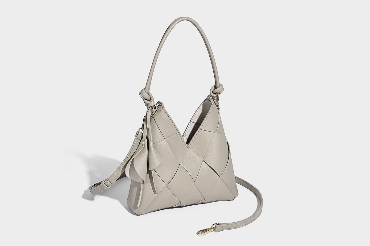 Compact bucket shoulder bag with black-and-white diamond patchwork panels, knotted top handle, gold-tone hardware, and
