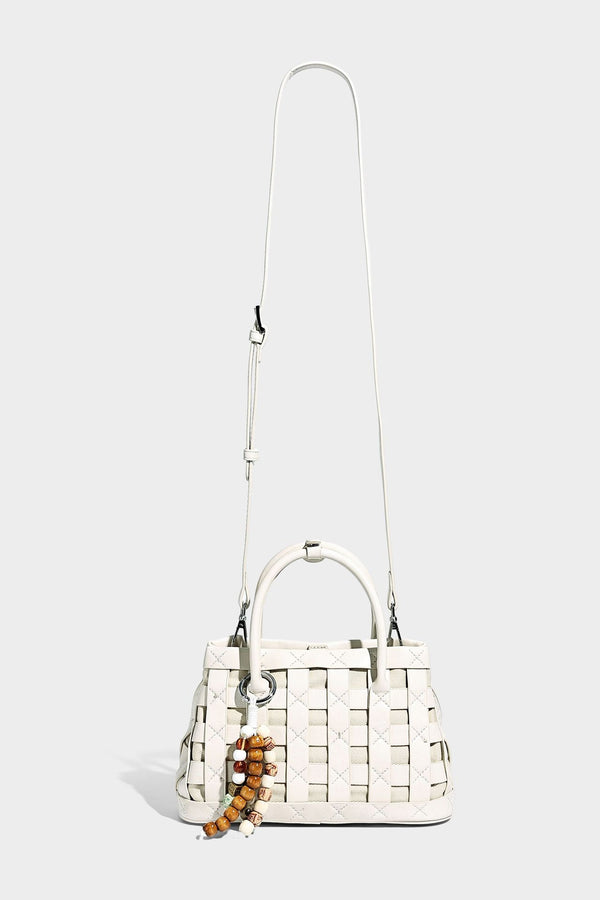 Small structured woven satchel tote with rounded top handles, silver-tone ring hardware, and bead tassel charm, detail view