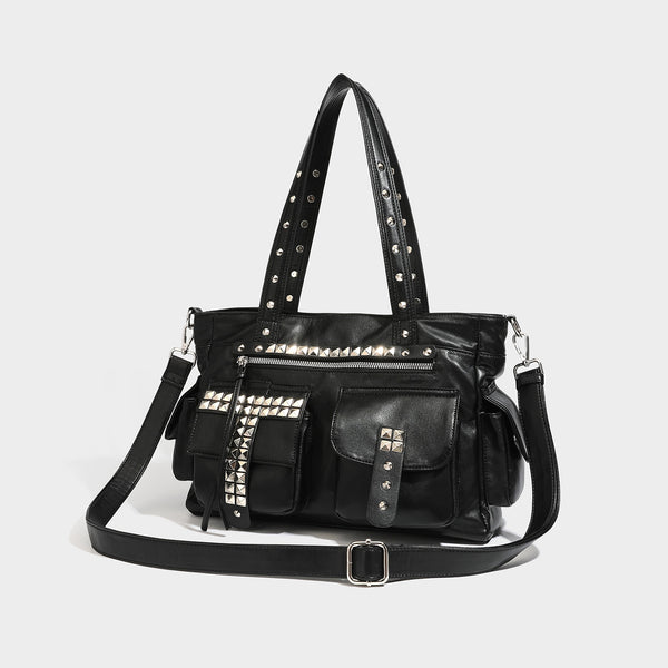 Black leather-look tote bag with silver pyramid studs on handles and front panel, multiple flap and zip exterior pockets