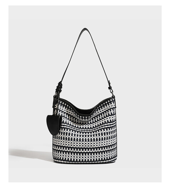Woven stripe bucket shoulder bag in cream and dark brown with leather-look trim, knotted adjustable strap, and small shield