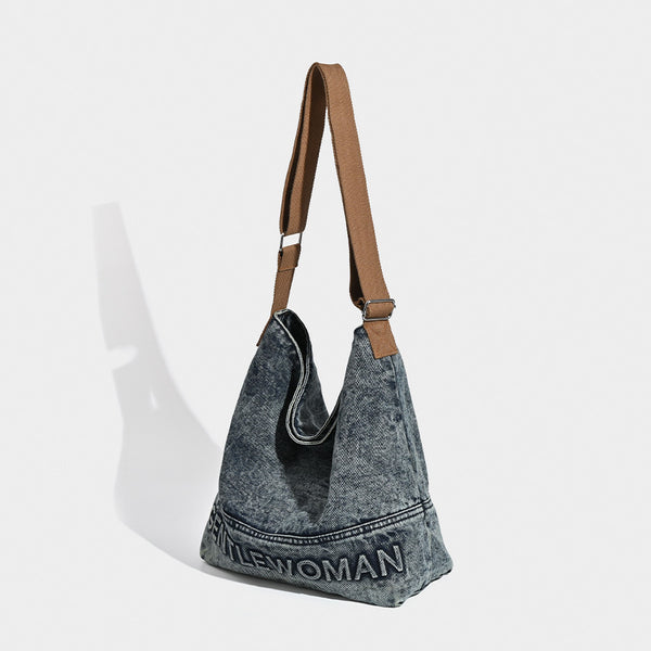 Washed blue denim slouchy open-top shoulder tote bag with tan leather-look adjustable crossbody strap and embroidered, detail