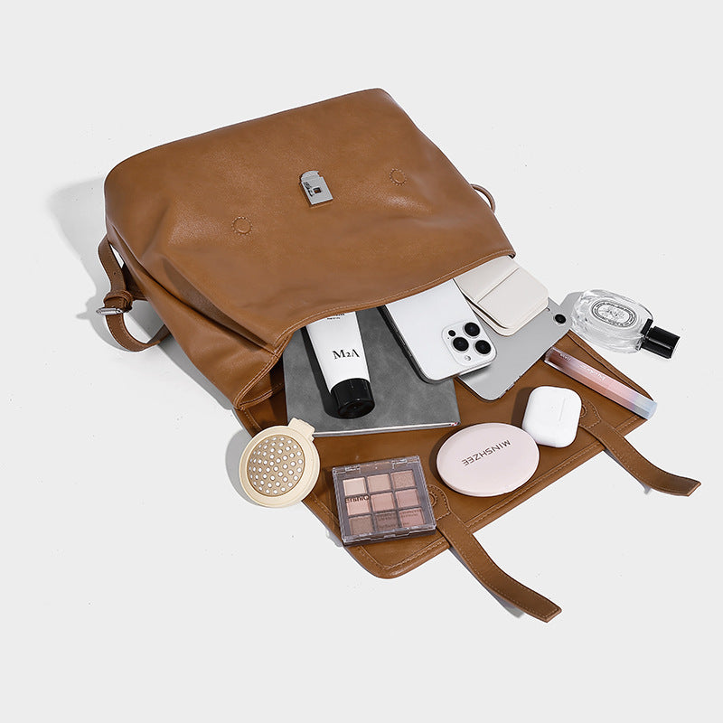 Structured tan leather-look flap backpack handbag with top handle, silver buckle hardware, and fold-over front closure
