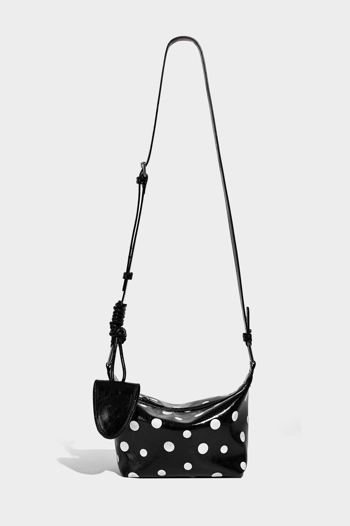 Kompakte glänzende Hobo-Schultertasche in Schwarz mit weißen Punkten, Reißverschluss, Beschlägen in Gunmetal und befestigtem Überschlag vorne