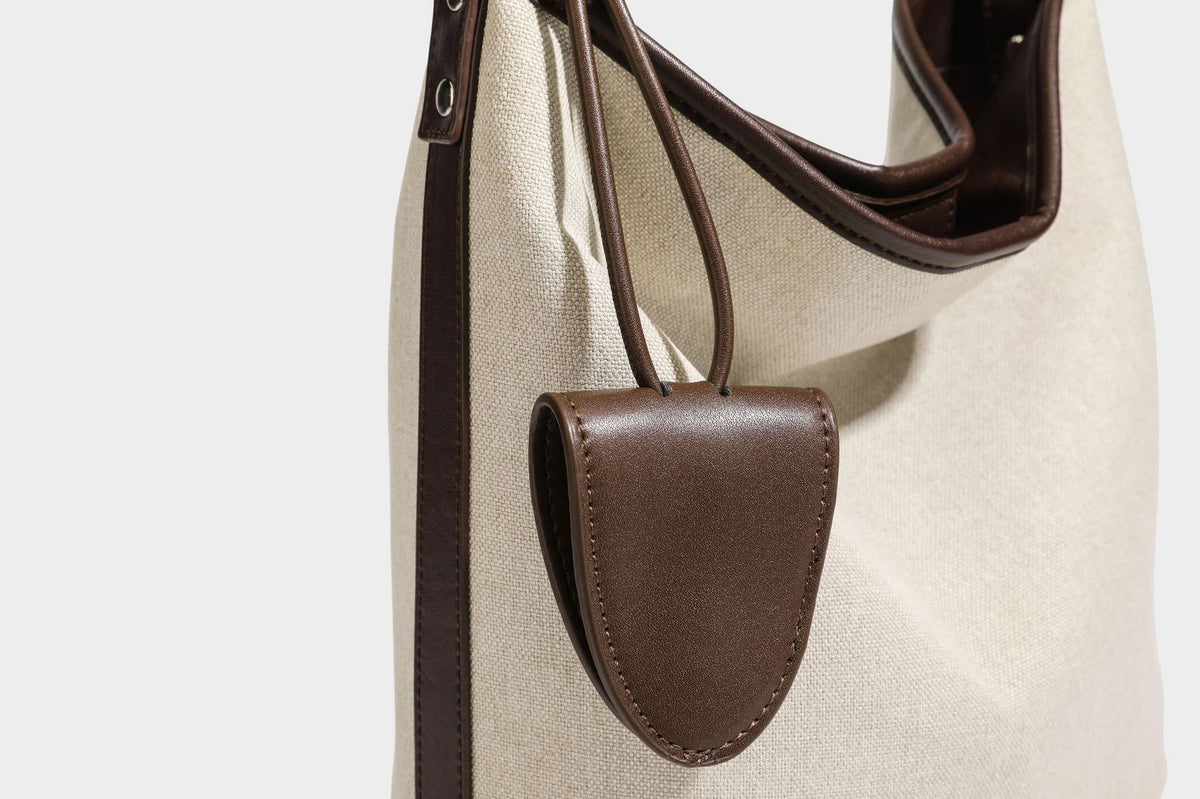 Oatfarbene Canvas-Schultertasche mit dunkelbraunem Besatz in Lederoptik, langem verstellbarem Riemen und angebrachter Mini-Tasche mit Überschlag, Detailansicht