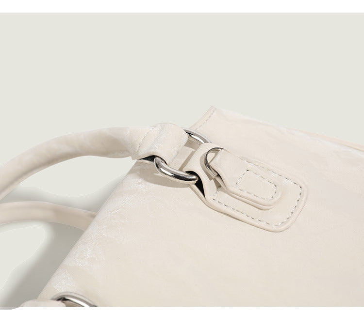 Small structured Boston bag in cream with glossy crinkled finish, sheer bow accent, silver-tone hardware, dual top handles