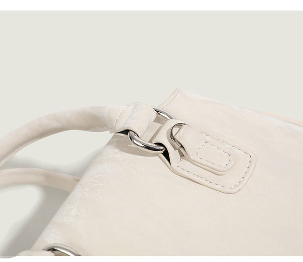 Small structured Boston bag in cream with glossy crinkled finish, sheer bow accent, silver-tone hardware, dual top handles