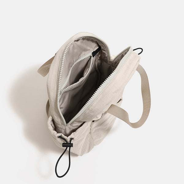 Small rounded mini backpack handbag in matte ripstop-texture fabric with top webbing handle, front pocket, side drawstring