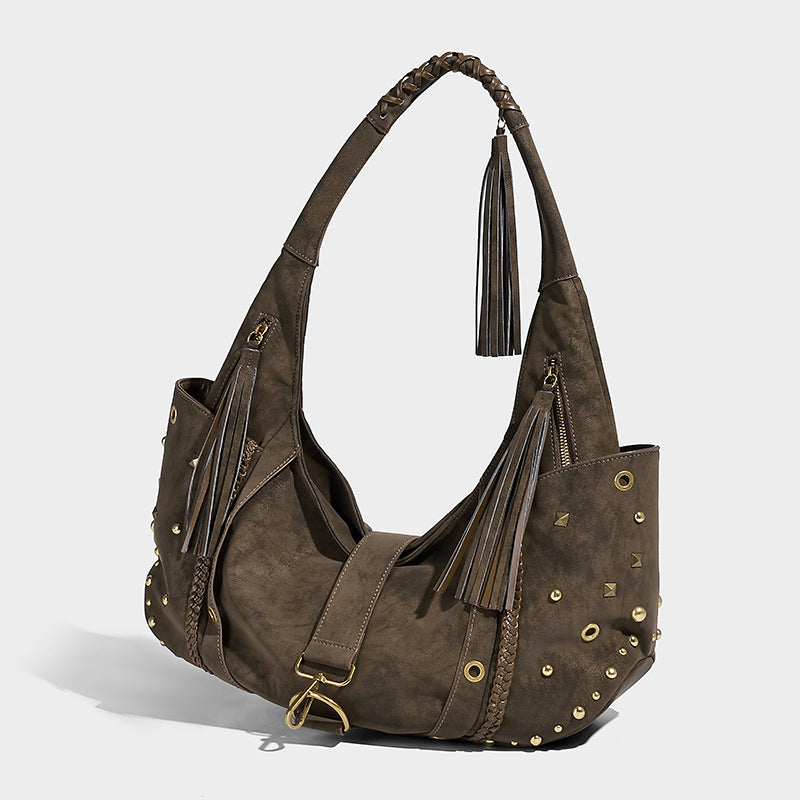 Slouchy crescent hobo bag in matte brown suede-like finish with gold-tone studs, grommets, braided top handle, tassel side