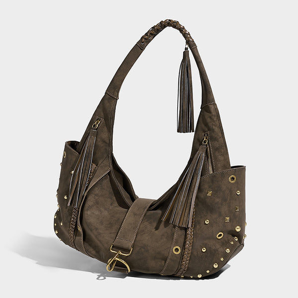 Slouchy crescent hobo bag in matte brown suede-like finish with gold-tone studs, grommets, braided top handle, tassel side