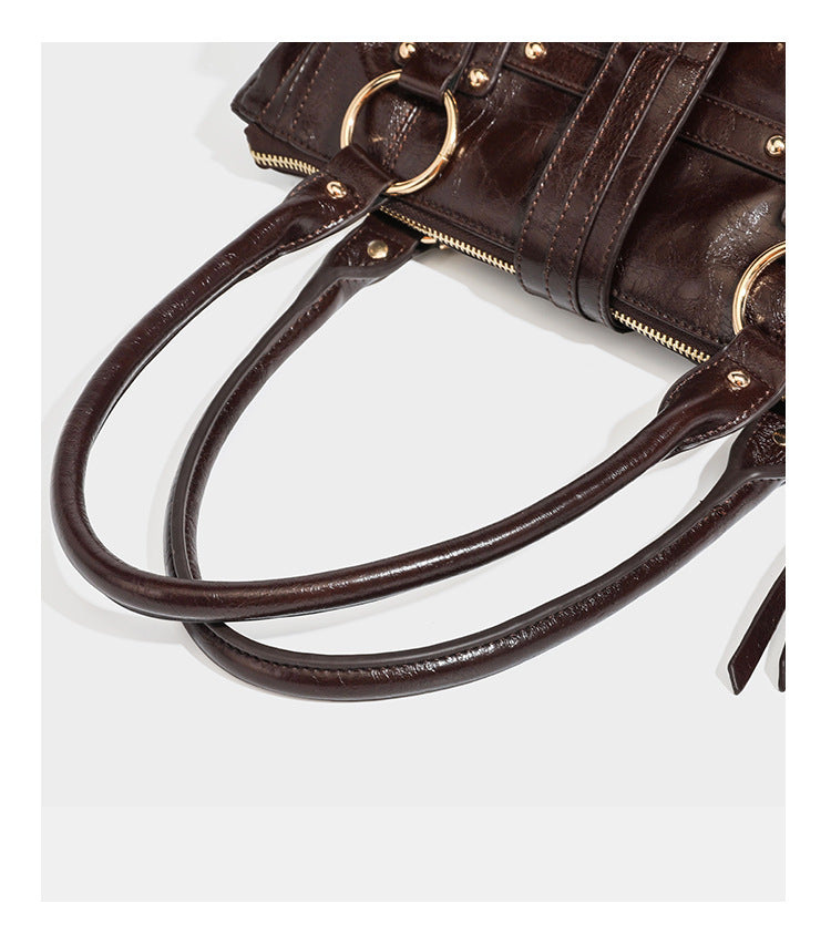 Dark brown glossy leather-look structured satchel tote with gold-tone studs, buckle straps, dual top handles, and detachable