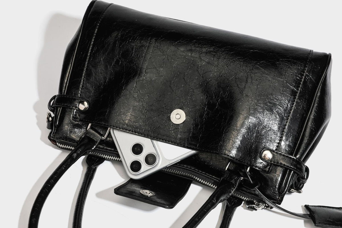 Structured glossy crinkled leather-look satchel with double top handles, front metal-plaque tab, silver-tone hardware, and