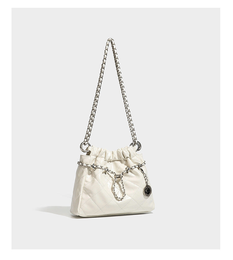 Glossy diamond-quilted drawstring bucket bag with silver chain shoulder strap and medallion charm, detail view 7