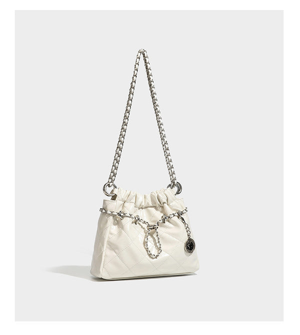 Glossy diamond-quilted drawstring bucket bag with silver chain shoulder strap and medallion charm, detail view 16