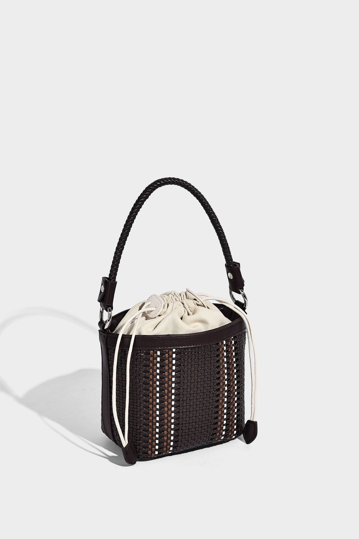 Small woven bucket bag with drawstring top, braided handle, detachable crossbody strap, and silver-tone ring hardware, detail
