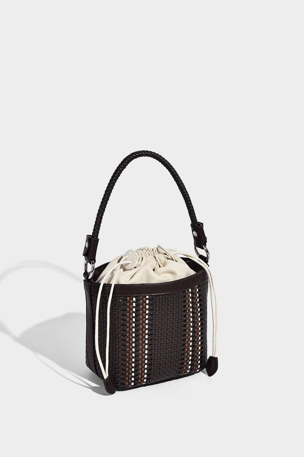 Small woven bucket bag with drawstring top, braided handle, detachable crossbody strap, and silver-tone ring hardware, detail