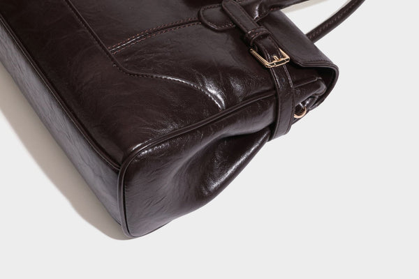 Structured glossy leather-look satchel bag with flap closure, gold-tone buckle accents, double top handles, detachable