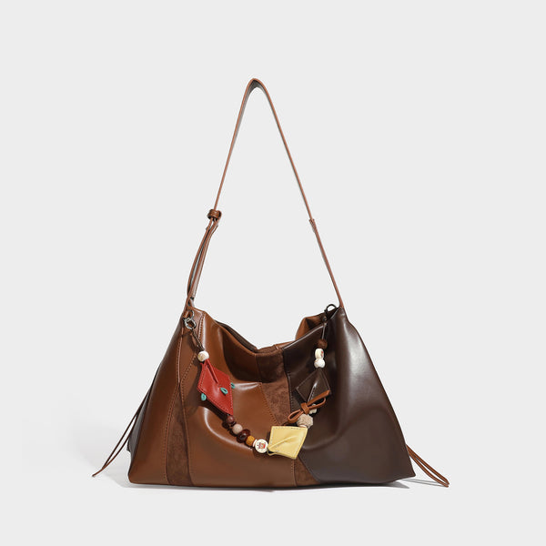 Two-tone black and brown leather-look slouchy shoulder bag with beaded tassel charm and silver-tone hardware, detail view 6