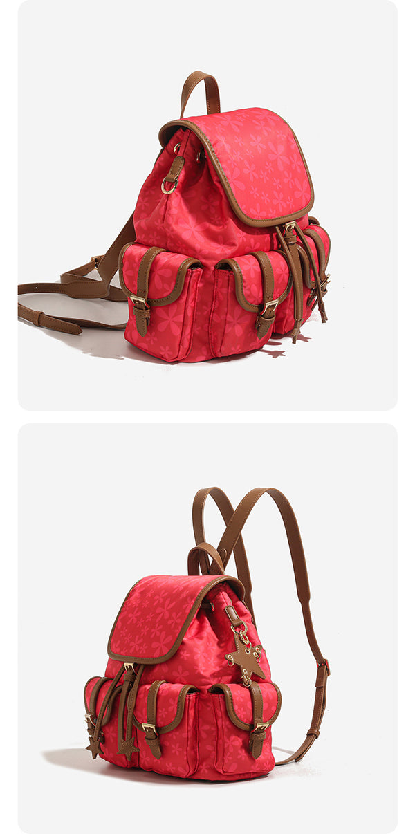 Red floral-print backpack handbag with brown leather-look trim, dual front buckle pockets, star charms, and gold-tone, detail