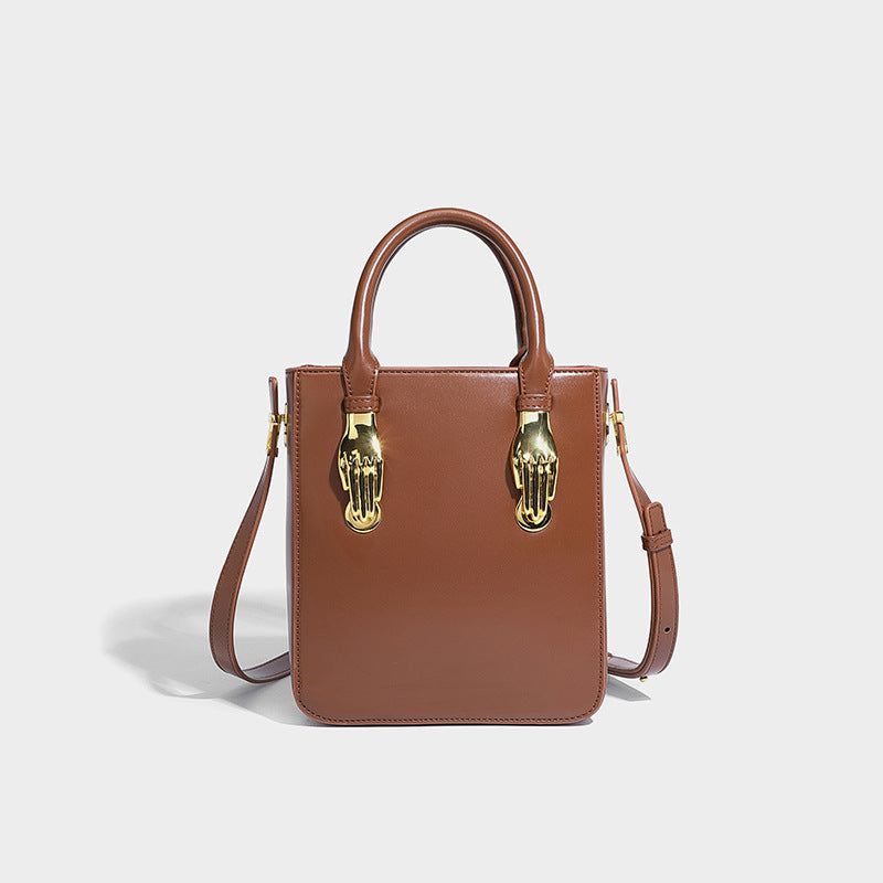 Kleine, strukturierte, kastenförmige Henkeltasche mit goldfarbenem, handförmigem Beschlag in schwarzer Lederoptik und abnehmbarem, Detailansicht
