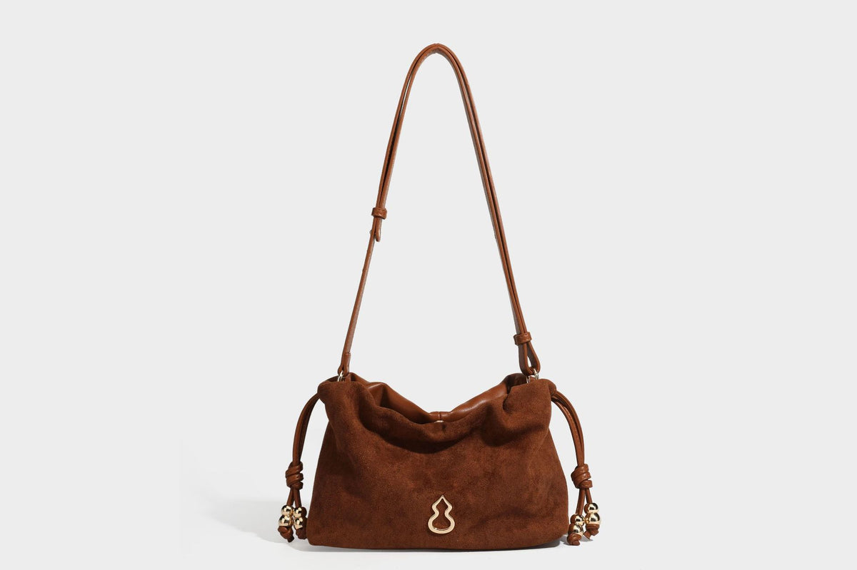 Suede-look drawstring shoulder bag in brown with smooth trim, knotted bead drawstring closure, slim adjustable strap, and