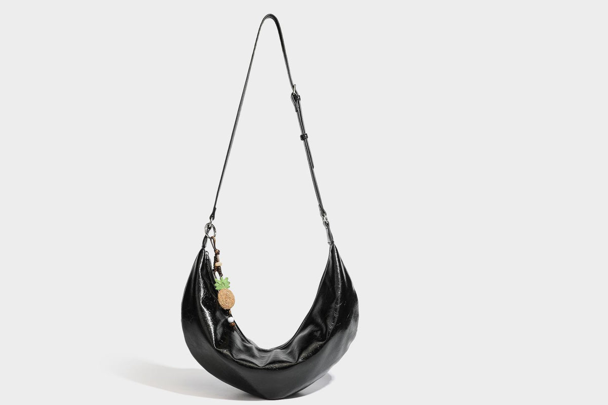 Legere, halbmondförmige Hobo-Schultertasche in glänzender, geknautschter Lederoptik mit schmalem Riemen, Ringbeschlägen in Silberoptik und