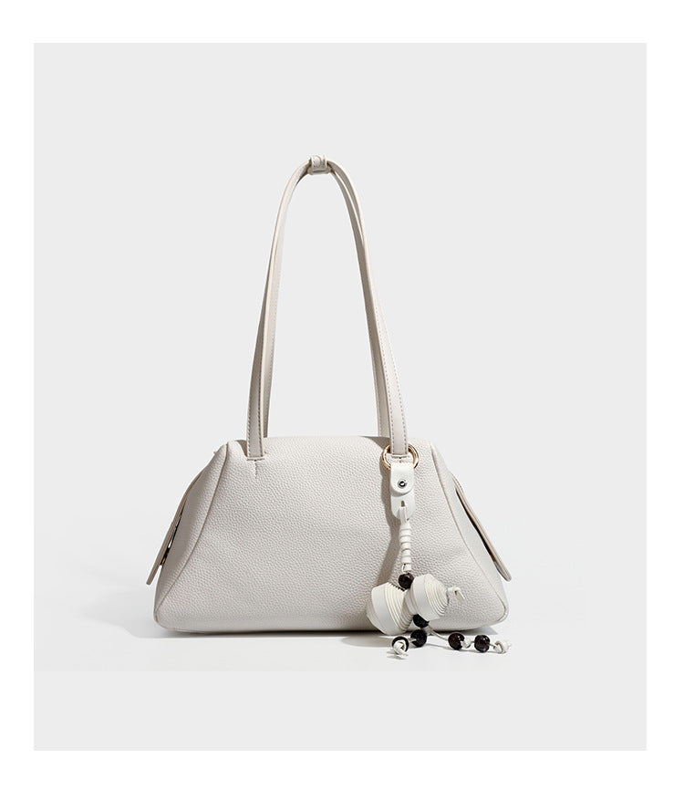 Structured trapezoid shoulder bag in dark brown pebbled leather-look finish with slim double straps, top zip closure, side