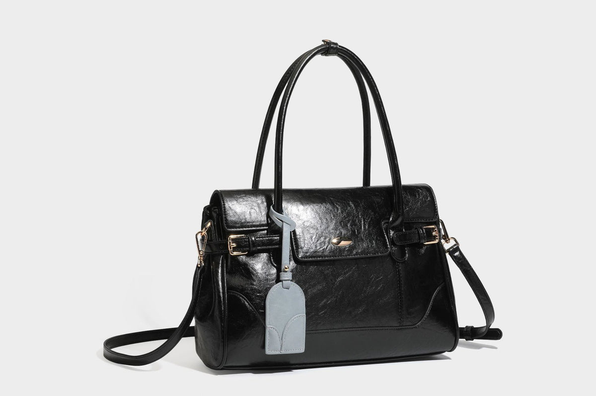 Structured glossy leather-look satchel bag with flap closure, gold-tone buckle accents, double top handles, detachable