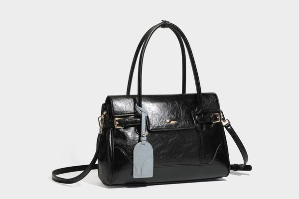Structured glossy leather-look satchel bag with flap closure, gold-tone buckle accents, double top handles, detachable