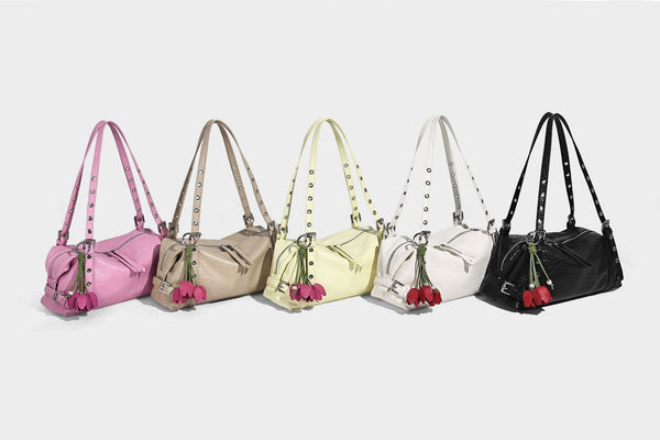 Pale yellow leather-look barrel bag with silver grommet-studded shoulder straps, top zip closure, and pink tulip floral