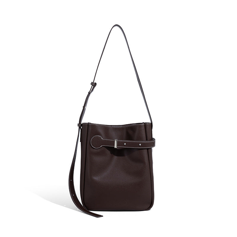 Structured dark brown leather-look bucket bag with white contrast stitching, front wraparound belt buckle strap, and long