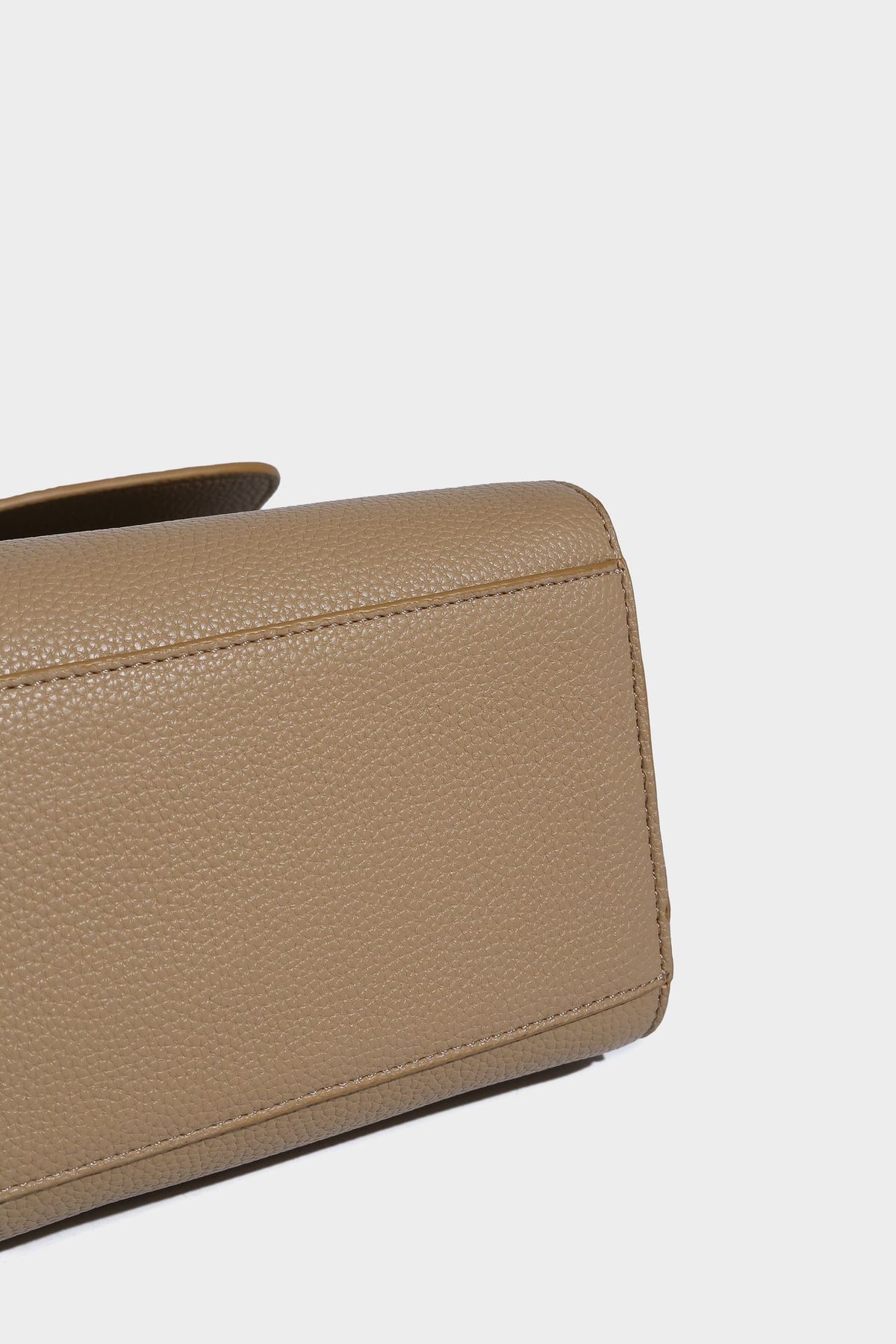 Strukturierte, trapezförmige Henkeltasche mit matt genarbter Oberfläche, vorderer Klappe und quadratischem Drehverschluss in Goldoptik, Detailansicht