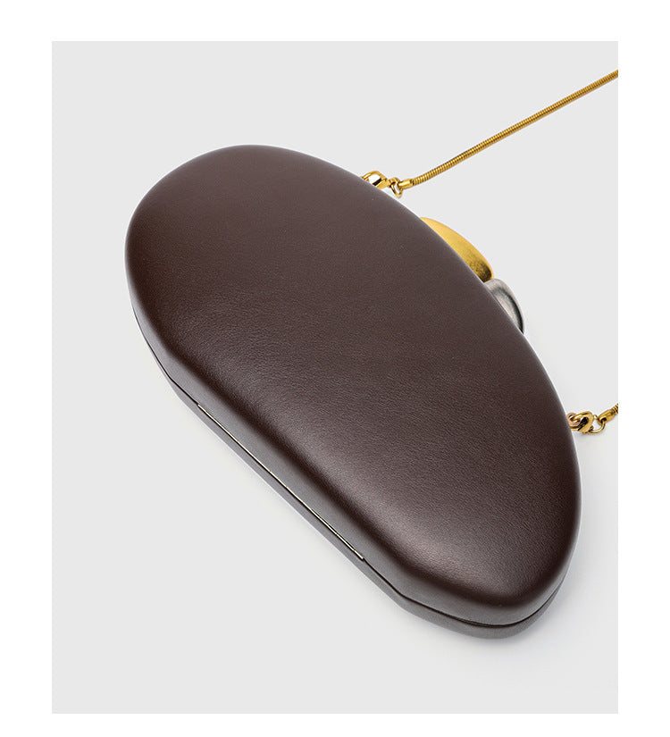 Oval hard-shell crossbody clutch bag with smooth matte leather-look finish and gold-tone snake chain strap, detail view 16