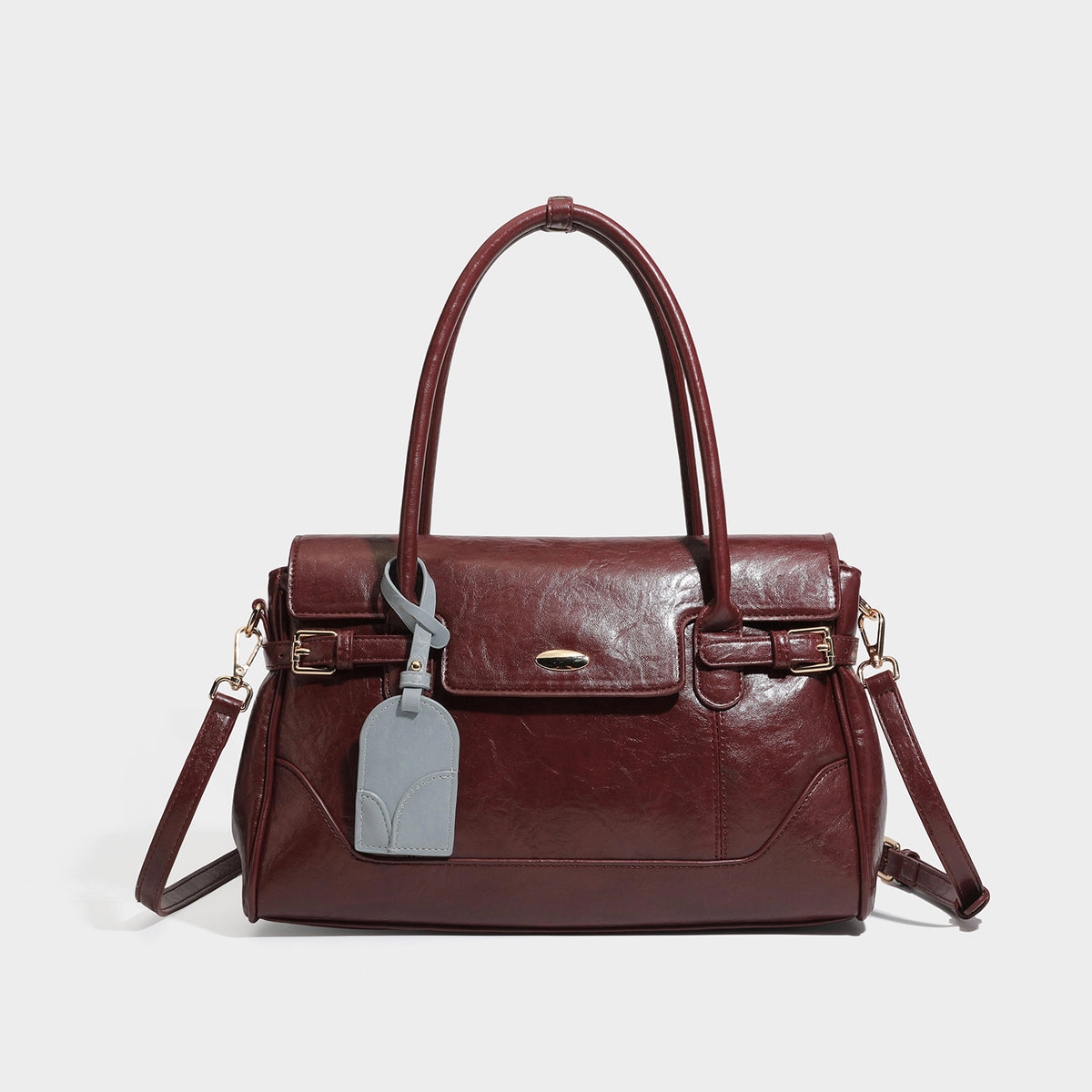 Structured glossy leather-look satchel bag with flap closure, gold-tone buckle accents, double top handles, detachable