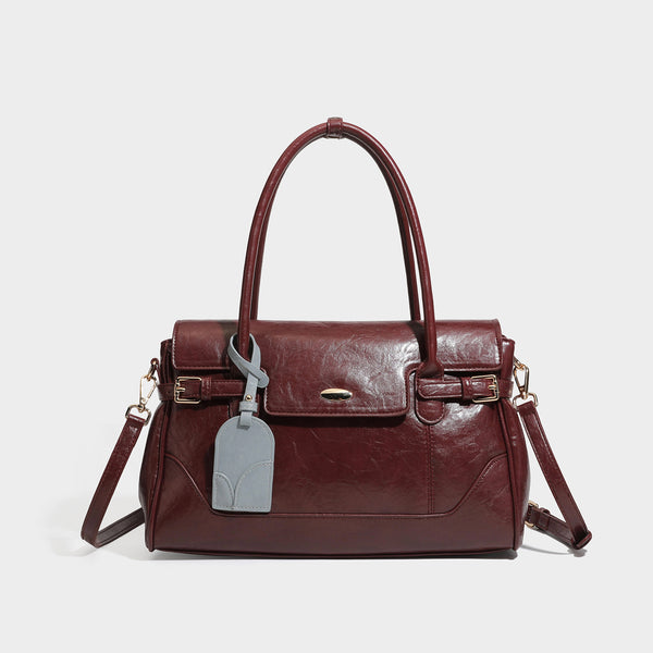 Structured glossy leather-look satchel bag with flap closure, gold-tone buckle accents, double top handles, detachable