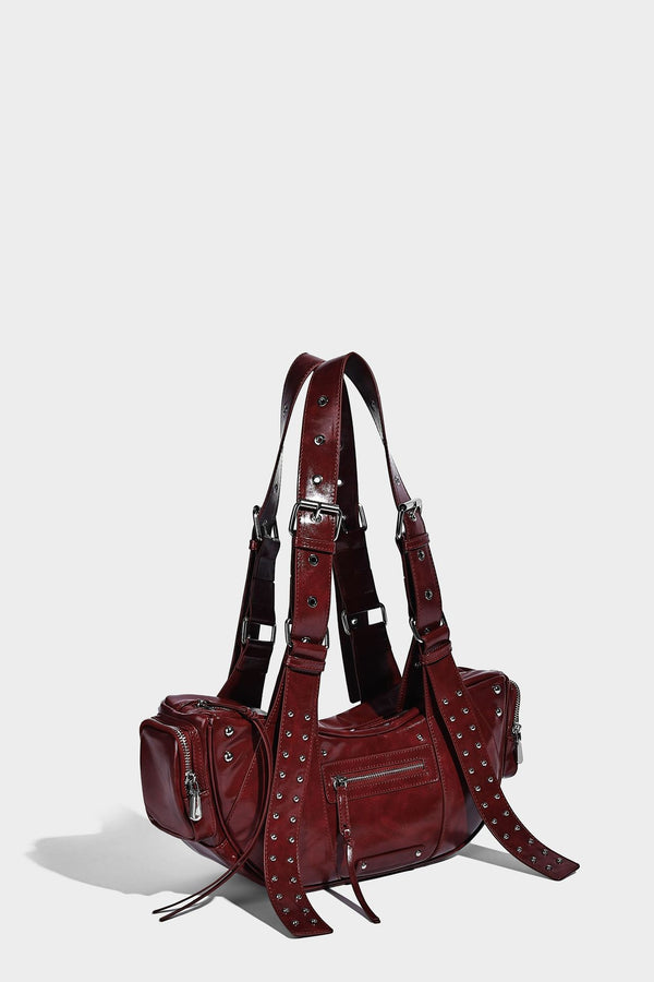 Glossy black crescent shoulder bag with silver-tone rivets, multiple zip pockets, and long adjustable studded straps, detail
