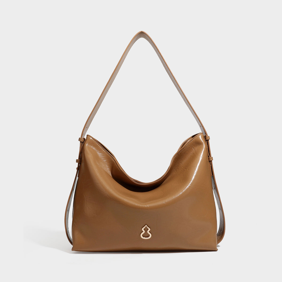 Lässig-sackförmige Hobo-Schultertasche mit offenem oberen Rand in glänzender karamellfarbener Lederoptik, goldfarbenen Logo-Beschlägen und langem verstellbarem