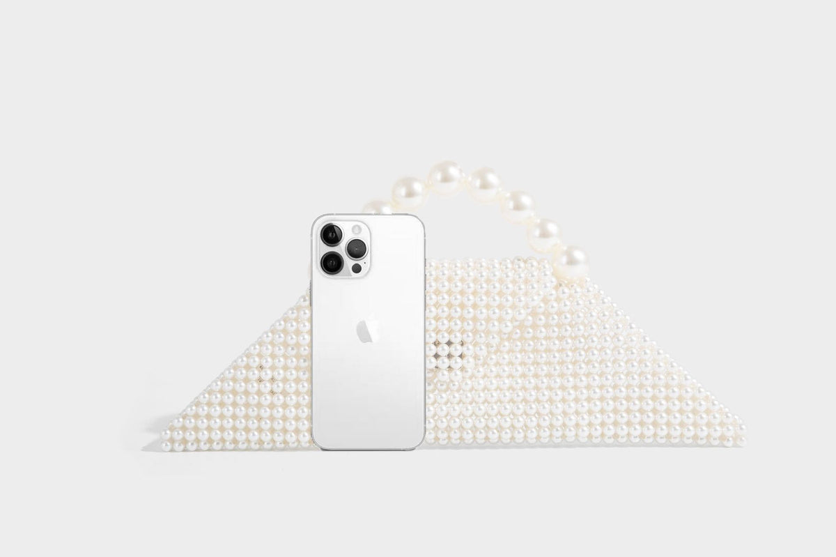 Small structured triangle clutch bag covered in glossy pearl beads with an arched pearl top handle and silver snap closure