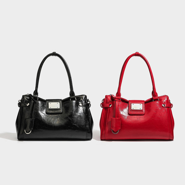 Structured glossy crinkled leather-look satchel with double top handles, front metal-plaque tab, silver-tone hardware, and