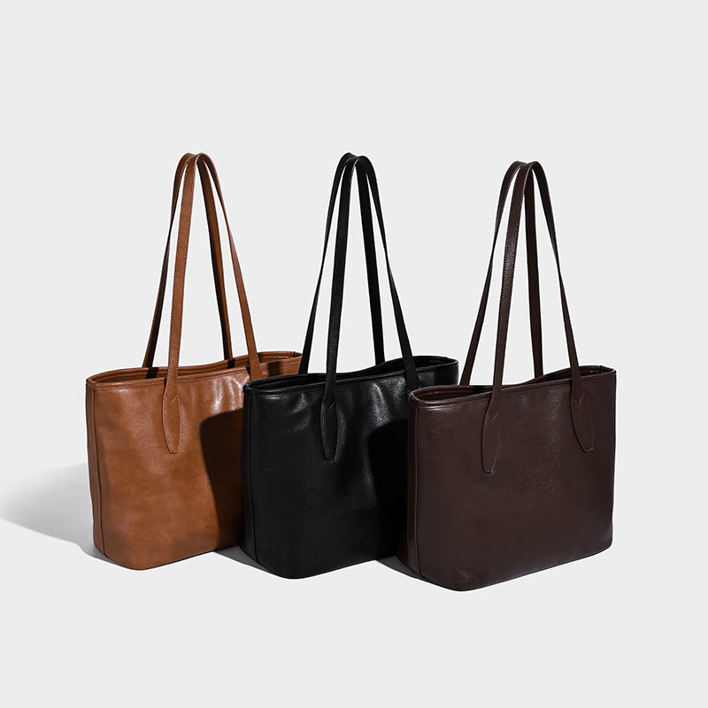 Large structured leather-look tote bag with double shoulder straps and metal tag hardware, detail view 2