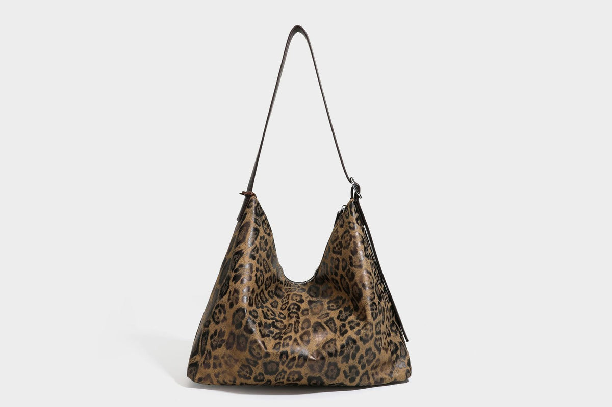 Slouchy leopard print hobo shoulder bag with glossy coated finish, top zipper closure, dark brown trim, and dangling charm