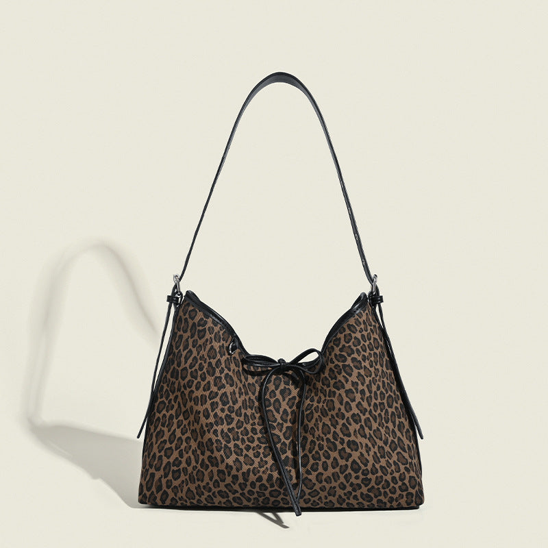 Slouchy hobo bag in brown and black leopard print with bow drawstring closure, black leather-look trim, and silver-tone stud