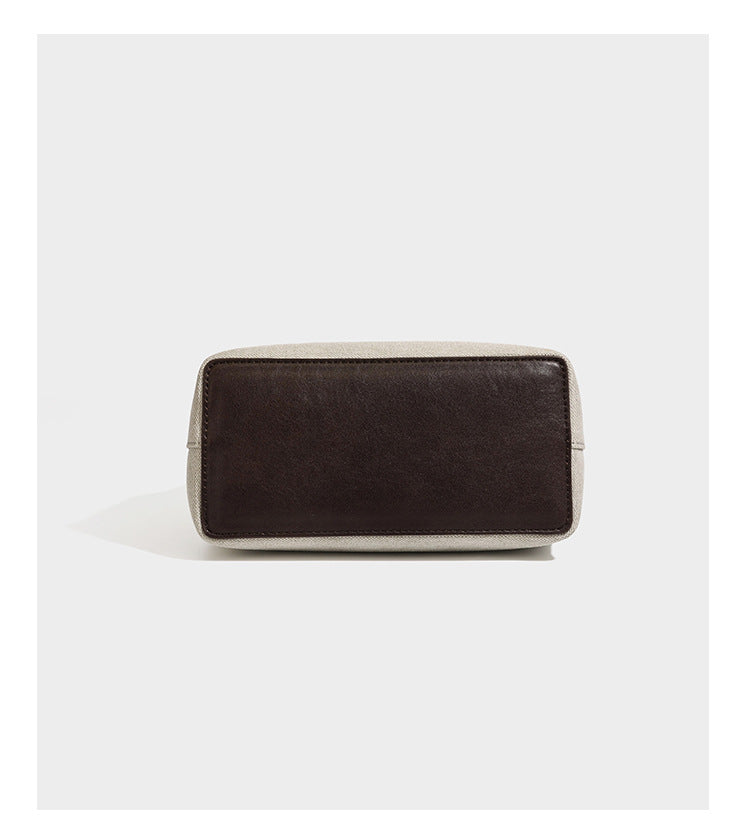 Small structured beige canvas top-handle bag with dark brown leather-look trim, silver turn-lock hardware, and detachable
