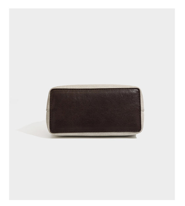 Small structured beige canvas top-handle bag with dark brown leather-look trim, silver turn-lock hardware, and detachable